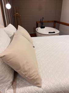 uma cama branca com uma almofada em cima em Lofts Urbano em Urubici