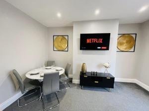 a dining room with a table and a tv on the wall at Serenity By The Sea, Stylish Two Bedroom Apartment Near The Beach, South Shields in South Shields