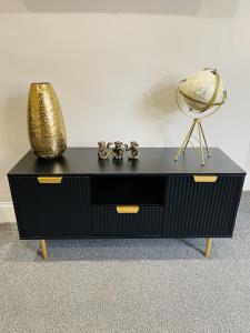a black dresser with a gold vase on top of it at Serenity By The Sea, Stylish Two Bedroom Apartment Near The Beach, South Shields in South Shields