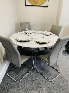 a white table with chairs and wine glasses on it at Serenity By The Sea, Stylish Two Bedroom Apartment Near The Beach, South Shields in South Shields
