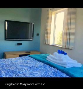 a bedroom with a bed with a tv and towels at Scrabo View - King Bedroom with private bathroom in Comber