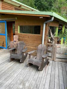 2 chaises assises sur une terrasse couverte d'une cabine dans l'établissement La pirogue enchantée, à Païta