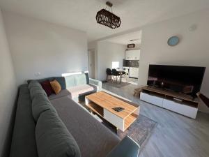 Sala de estar con sofá gris y TV en Villa JETA, en Prevallë