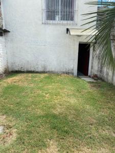 a building with a door and a grass yard at Habitación Juspe in Colonia del Sacramento