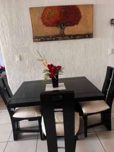 una mesa negra con dos sillas y un jarrón con flores en Residencia en Ciudad Guzmán, en Ciudad Guzmán