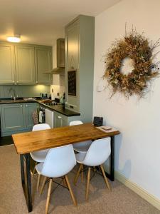 uma cozinha com uma mesa de madeira e cadeiras brancas em The Nest, central Ludlow one bed apartment em Ludlow