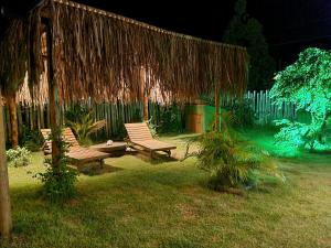 a group of benches sitting in a yard at night at Pousada TAUANE in Caraíva