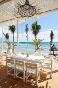 a table and chairs on a beach with the ocean at Luxurious Tulum Terrazas 2-bedroom Condominiuml in Akumal