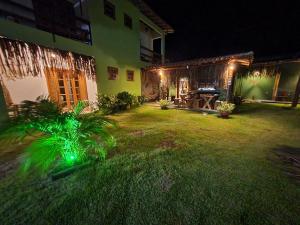 a yard with green plants and a house at night at Pousada TAUANE in Caraíva