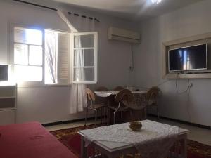 een woonkamer met een tafel en stoelen en een televisie bij Home2Home in Nabeul