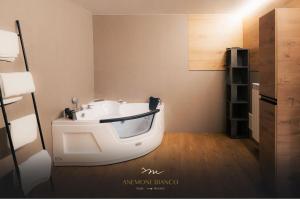 um quarto com uma banheira branca no canto de um quarto em Anemone Bianco Suite Rooms em Passo del Tonale