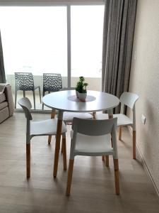 una mesa y sillas blancas en una habitación con ventana en Frente al mar con pileta en Quequén