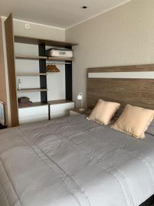 1 dormitorio con 1 cama grande y cabecero de madera en Frente al mar con pileta en Quequén