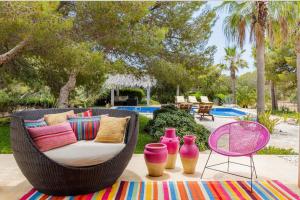 a wicker couch with colorful pillows and vases on a rug at Villa Leonor in Es Caló