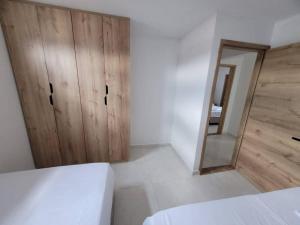 a white bedroom with a wooden cabinet and a mirror at Hermoso apto cerca al centro in Cartago