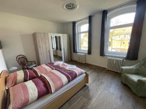 um quarto com uma cama, uma cadeira e 2 janelas em geräumige Ferienwohnung „Zum alten Forstamt“ em Clausthal-Zellerfeld