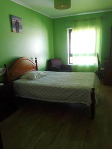 a green bedroom with a bed and a chair at Casa Modesta II in Beja