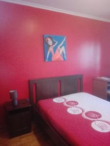 Un dormitorio con una cama roja con una foto en la pared en Casa Modesta II, en Beja