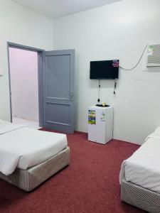 a room with two beds and a flat screen tv at لينا للوحدات السكنية المفروشة in Al Madinah
