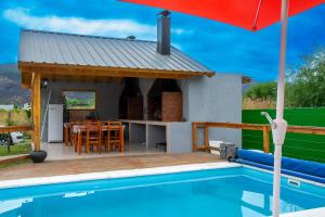 a villa with a swimming pool and a house at Cabañas & Apart Del Sauce in El Hoyo