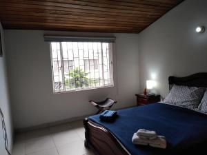 Schlafzimmer mit einem Bett mit blauer Bettwäsche und einem Fenster in der Unterkunft Hostal Norma101 in Bogotá