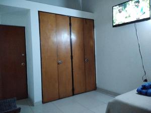 Habitación con armario de madera y TV. en Hostal Norma101, en Bogotá