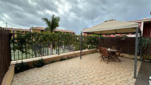 um pátio com um guarda-sol, uma mesa e cadeiras em Cómodo apartamento en El Palm mar em Palm-mar