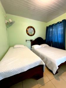 two beds in a room with blue curtains and a mirror at Miravalles Volcano House in Guayabal