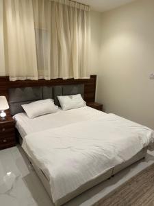 een slaapkamer met een groot wit bed en een raam bij شقة فاخرة بدخول ذاتي 2 in Al Kharj