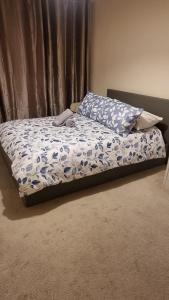 an unmade bed in a bedroom with a bedspread with flowers at Two bed Apartment free parking near Colindale Station in Colindale