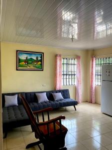 a living room with a blue couch and a refrigerator at Miravalles Volcano House in Guayabal