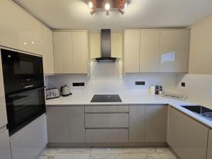 una cocina con armarios blancos y un aparato negro en New 2 Bedroom Appartment In Manchester - Stretford - Old Trafford Close to Football-Cricket Ground & City Centre, en Mánchester