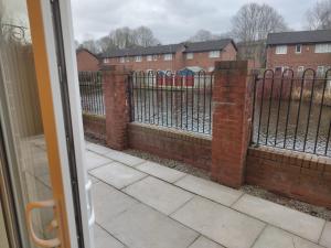 uma vista para uma cerca com uma parede de tijolos em New 2 Bedroom Appartment In Manchester - Stretford - Old Trafford Close to Football-Cricket Ground & City Centre em Manchester