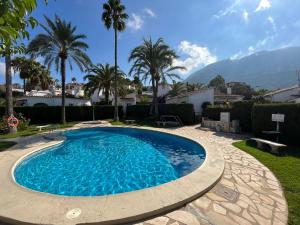 a swimming pool in a yard with palm trees at Bungalow en Denia in Denia