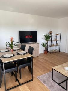 a living room with a table and chairs and a tv at Appartement 59m2 professionnel ou familial Saint Quentin en Yvelines in Montigny-le-Bretonneux