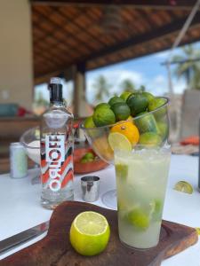 a drink and a bowl of limes and a bottle of alcohol at Casa São Miguel dos Milagres in São Miguel dos Milagres