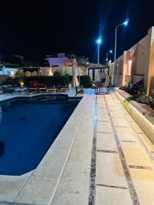 a swimming pool at night with lights on a building at Alis Villa in Hurghada