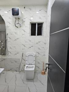 a bathroom with a toilet and a television on the wall at Hencapservices 001HPS in Agege