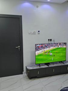a flat screen tv sitting in a room with a soccer game at Hencapservices 001HPS in Agege