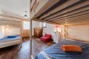 a bedroom with two bunk beds and a red chair at Grand Appartement dans Chalet Serre Chevalier à 8 minutes des pistes in Saint-Chaffrey