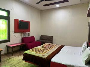 a bedroom with a bed and a chair and a tv at Hotel Skylark in Amritsar