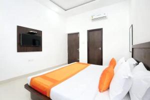 a bedroom with a large white bed with an orange pillow at Hotel Skylark in Amritsar