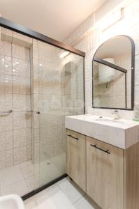a bathroom with a shower and a sink and a mirror at Spacious Apartment Located In Downtonwn Asuncin in Asunción