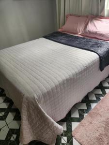 Una cama con manta blanca y almohadas rosas. en Casa favorita, en São Raimundo Nonato