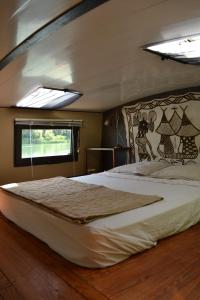 a large bed in a room with a window at Péniche Espoir in Avignon