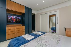 a bedroom with a tv and a bed with blue walls at Confortável Studio com 46,72m² in Florianópolis