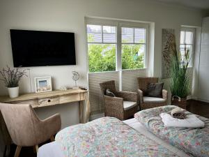 une chambre avec un lit, des chaises et une télévision dans l'établissement Ferienhaus-Sliminde-by-Seeblick-Ferien-direkte-Wasserlage-E-Ladesaeule-Sauna, à Olpenitz