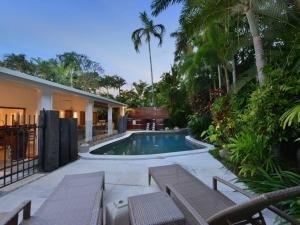uma piscina num quintal com bancos e uma casa em 9 Solander Boulevard em Port Douglas