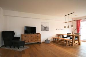 a living room with a television and a wooden table at Allgäustüble am See in Schwangau
