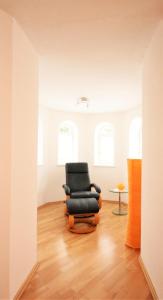 プフロンテンにあるFerienwohnung Alpenroseのウッドフロアの客室で、黒い椅子